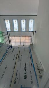 An interior hallway or landing with black metal railings and floor protection during installation by Advanced Welding All in One Fabrication LLC in Guttenberg, NJ.