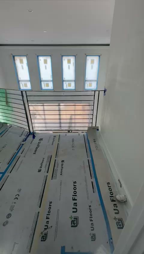 An interior hallway or landing with black metal railings and floor protection during installation by Advanced Welding All in One Fabrication LLC in Guttenberg, NJ.