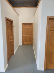 A renovated interior hallway with fresh white paint, new trim, and grey flooring by Joe Norton's Handyman Service in Williston, ND.