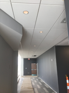 An interior hallway under renovation with new ceiling tiles and protective floor covering by Combs Interior Specialties in Columbus, OH.