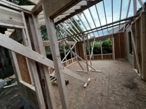 Interior view of a house addition under construction, showing wooden wall studs and roof framing by B & S Development, Inc. in Richmond, VA