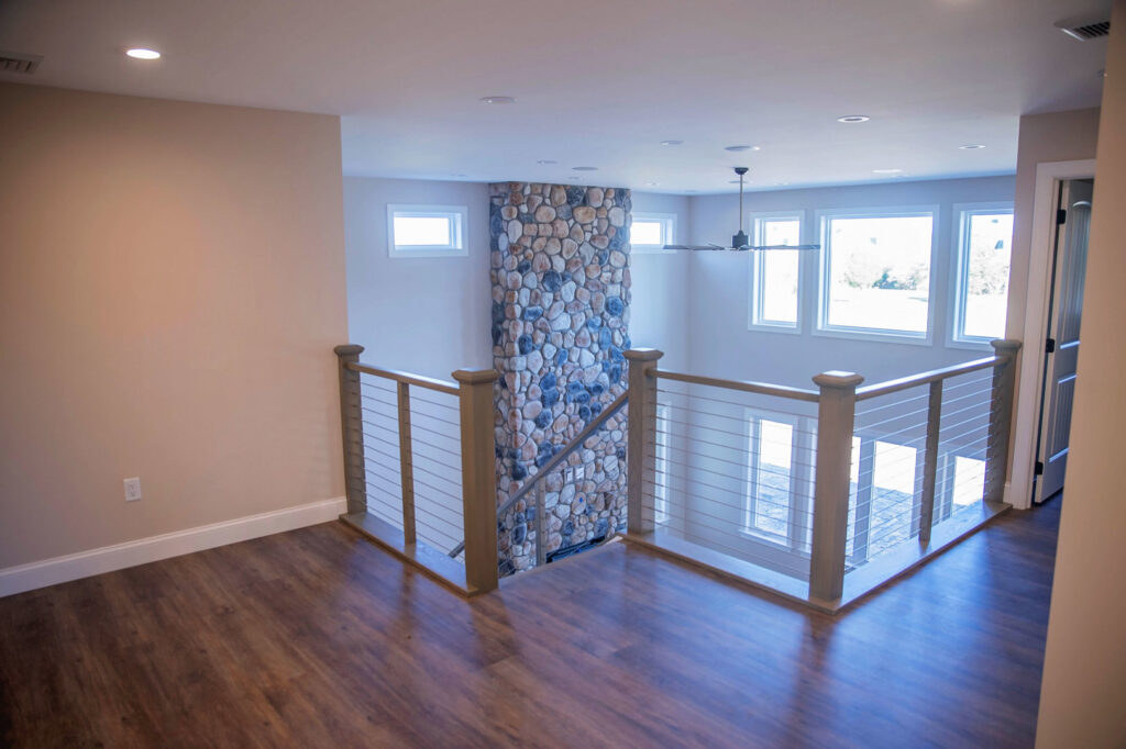 An interior loft area featuring a striking stone column and modern railing by Corrado Custom Homes, Inc. in Kutztown, PA