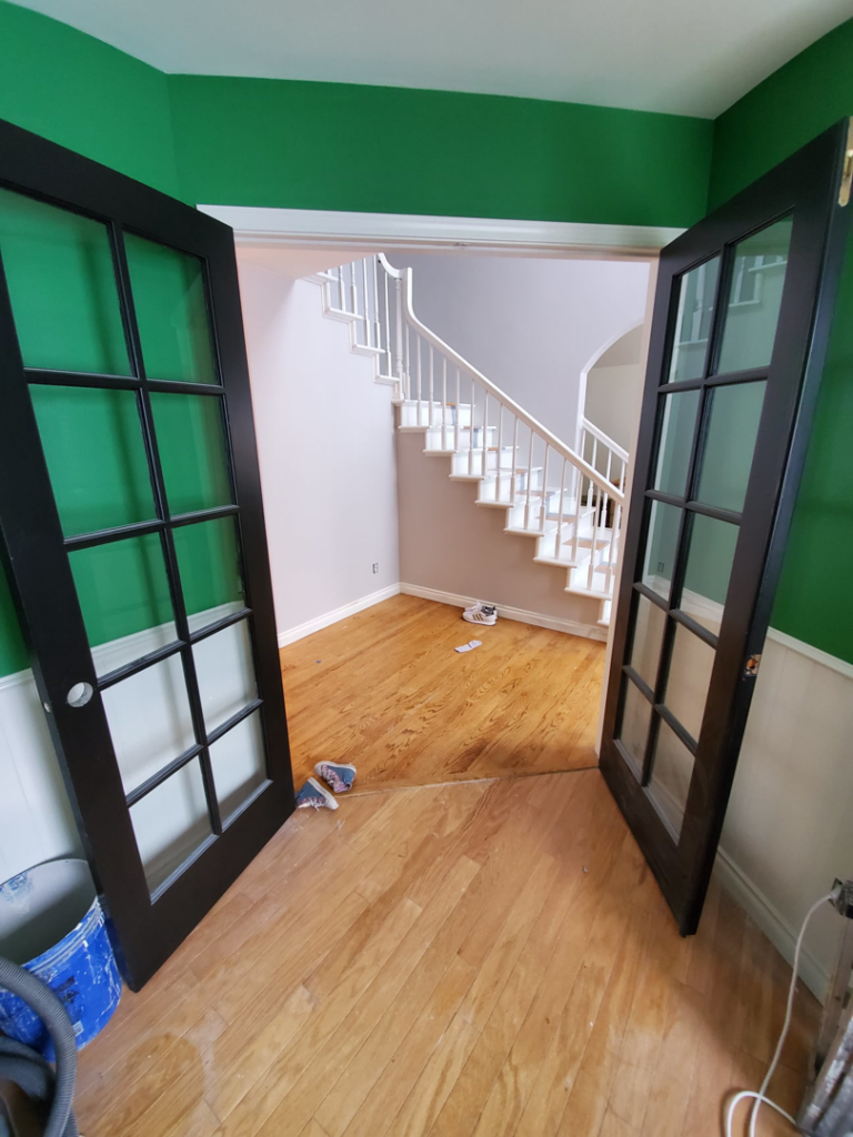 A room with newly painted green walls, white wainscoting, and black French doors installed by Lilac Remodel Spokane in Spokane Valley, WA.