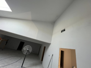 Freshly painted interior walls and high ceilings, with a fan for drying, showcasing painting services by Brown & Son Contracting in O'Fallon, MO.