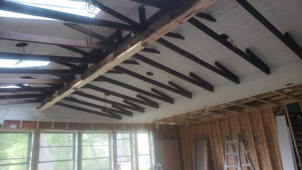 An interior renovation project showing exposed ceiling beams and new white panels by Ironside Home Improvements, LLC in Madison, WI.