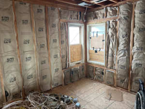 An interior renovation project featuring wall insulation, exposed studs, and electrical wiring by Kliesen Construction Company in Pueblo, CO.