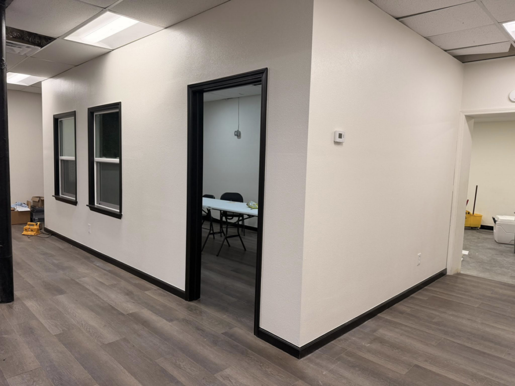 Newly renovated interior space with fresh paint, black trim, and new flooring by Yes Roofing & Construction Llc in Tulsa, OK.