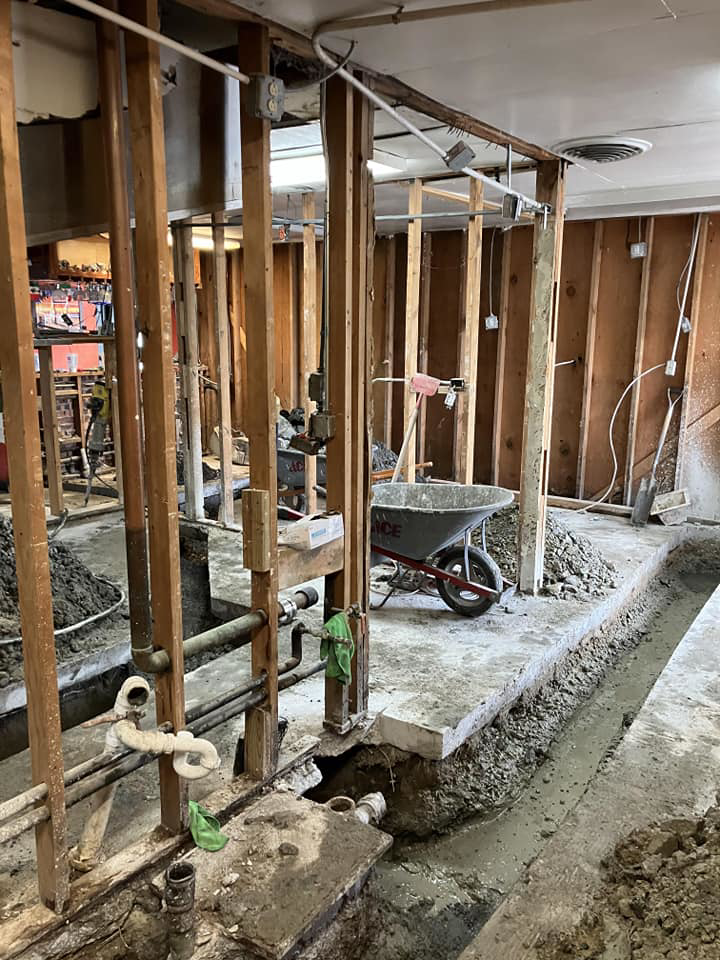 An interior renovation project showing exposed studs, plumbing, and floor trenches by JB Renovations in Houston, TX.