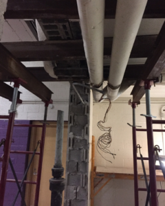 An interior renovation site showing exposed pipes and structural supports by DKI Demolition in West Bloomfield Township, MI.