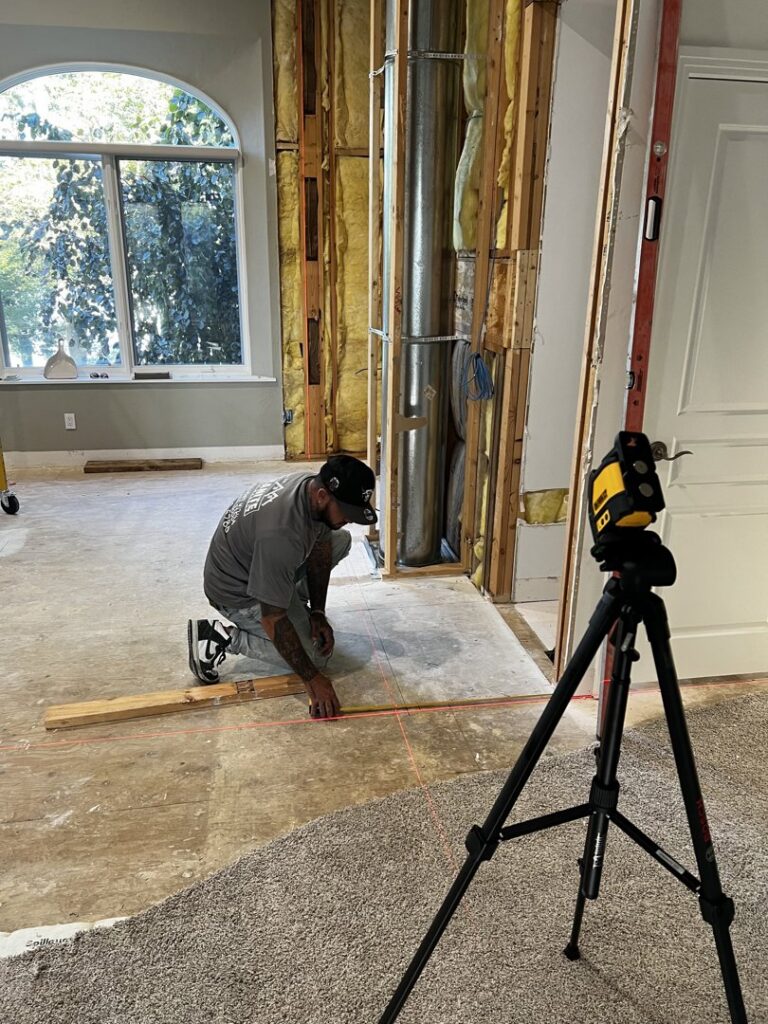 A worker precisely measuring the floor during an interior renovation project, showcasing framing work by Midwest Home Remodeling & Design LLC in Chicago, IL.