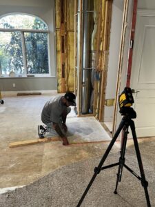 A worker precisely measuring the floor during an interior renovation project, showcasing framing work by Midwest Home Remodeling & Design LLC in Chicago, IL.