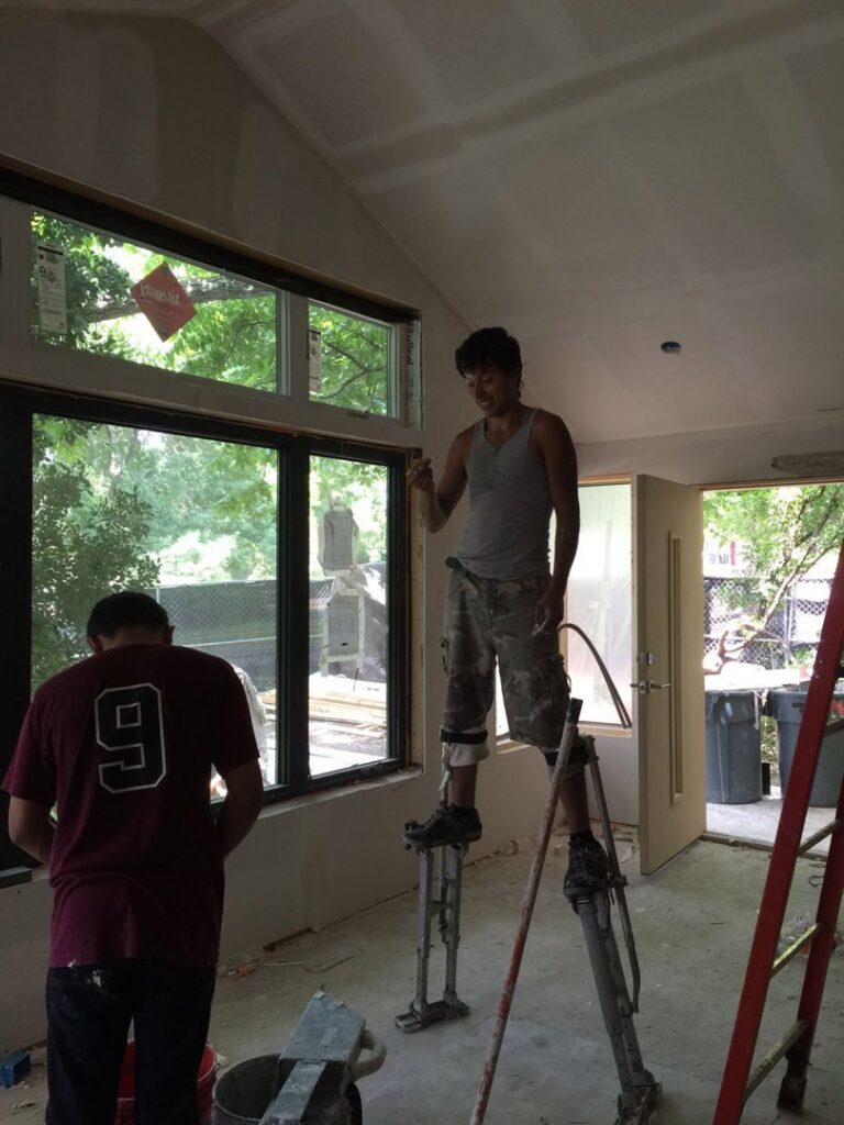 Workers performing interior construction, including drywall and window installation, managed by Savala's Remodeling Services in Austin, TX.