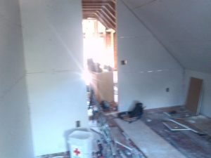 An interior room with new drywall installed and an open doorway, indicating ongoing construction by Sanow Construction in Huron, SD.