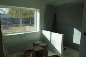 An interior room under construction, showing drywall installation and a new window by Kelso Custom Builders, Inc. in Phoenix, AZ.
