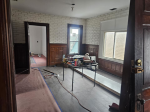 An interior room with new brick-patterned wallpaper, wainscoting, and a work table, showing finishing work by Done Well Home Improvement LLC in Buffalo, NY.
