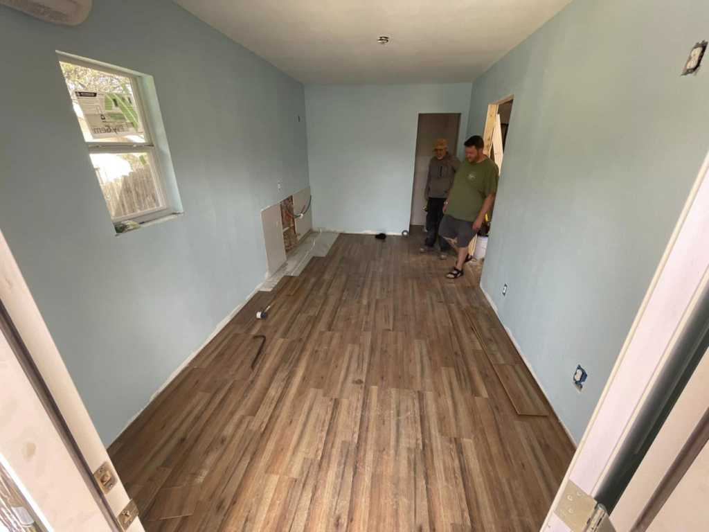 Workers from J8 General Construction installing new wood-look flooring in an interior room in San Antonio, TX.