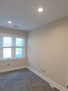 A freshly painted interior room with recessed lighting and a window by Albis Morales Painting LLC in Raleigh, NC.