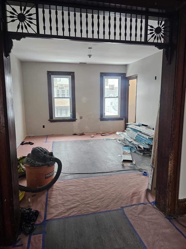 An interior room undergoing renovation with new flooring materials and a shop vac, by Done Well Home Improvement LLC in Buffalo, NY.
