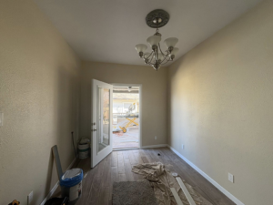 An interior room undergoing renovation with new flooring, painted walls, and a new light fixture by EJL Construction, LLC in Roswell, NM.