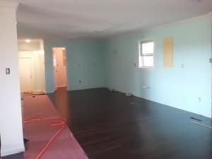 An interior room undergoing renovation with newly painted light blue walls and dark flooring by The House Doctor in Hopkinsville, KY.