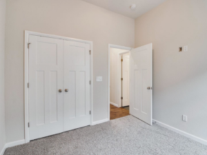 A newly renovated interior room with fresh carpet and white doors by Power Roofing & Construction in Norman, OK.