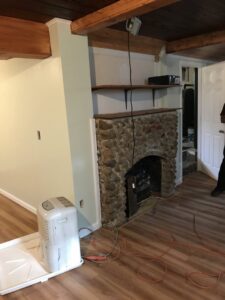 An interior room undergoing renovation, featuring a stone fireplace and new flooring, by Advanced Seamless Gutters, Inc. in Chicopee, MA.