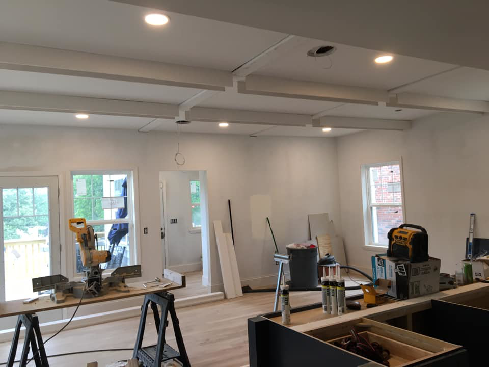 An interior room undergoing renovation with new ceiling beams, recessed lighting, and tools by DSD Construction in Saint Louis, MO.