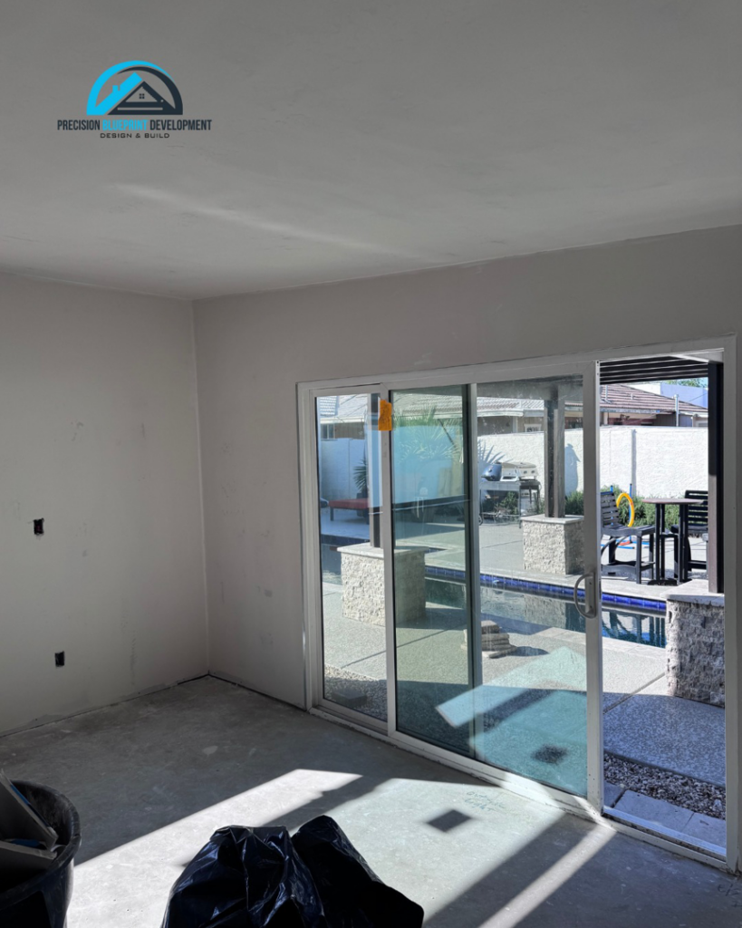 An interior room with new drywall and a large sliding glass door leading to a patio by Precision Blueprint Design & Development in San Tan Valley, AZ.