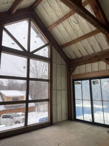 An interior room with spray foam insulation on walls and ceiling, offering a view of a snowy landscape by Spray Foam Art-Insulation in Stamford, CT.