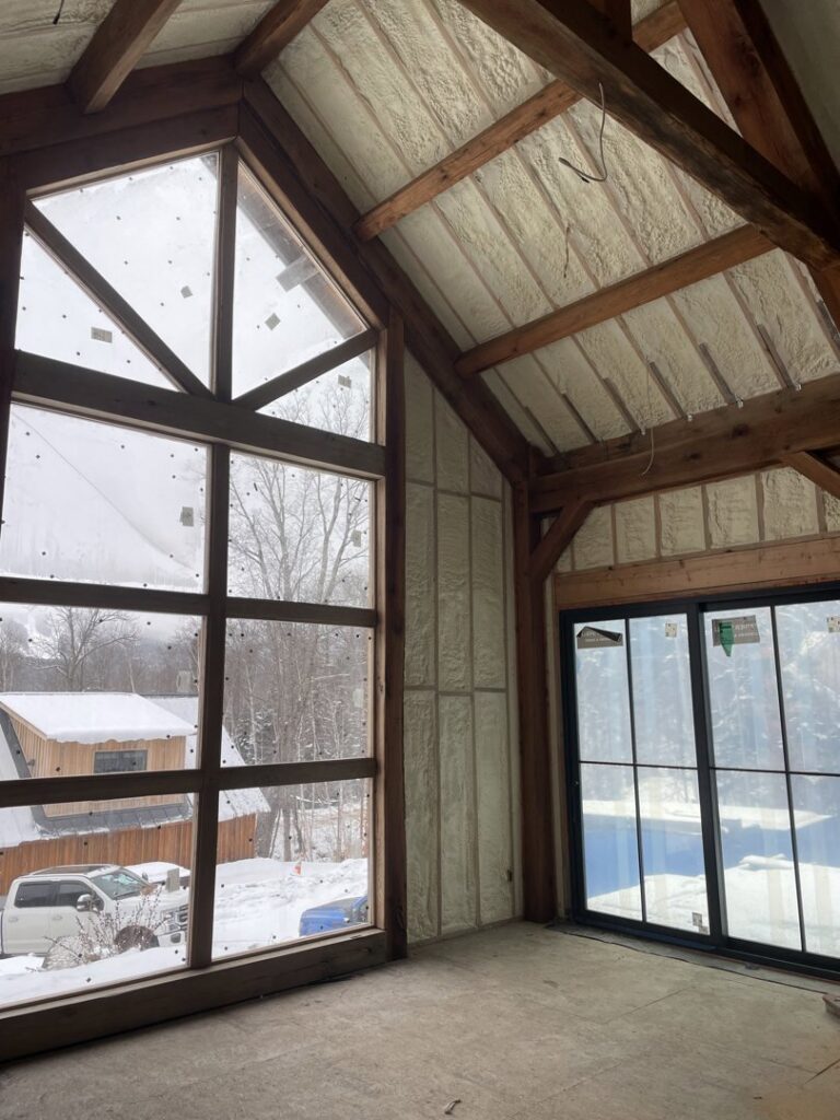 An interior room with spray foam insulation on walls and ceiling, offering a view of a snowy landscape by Spray Foam Art-Insulation in Stamford, CT.