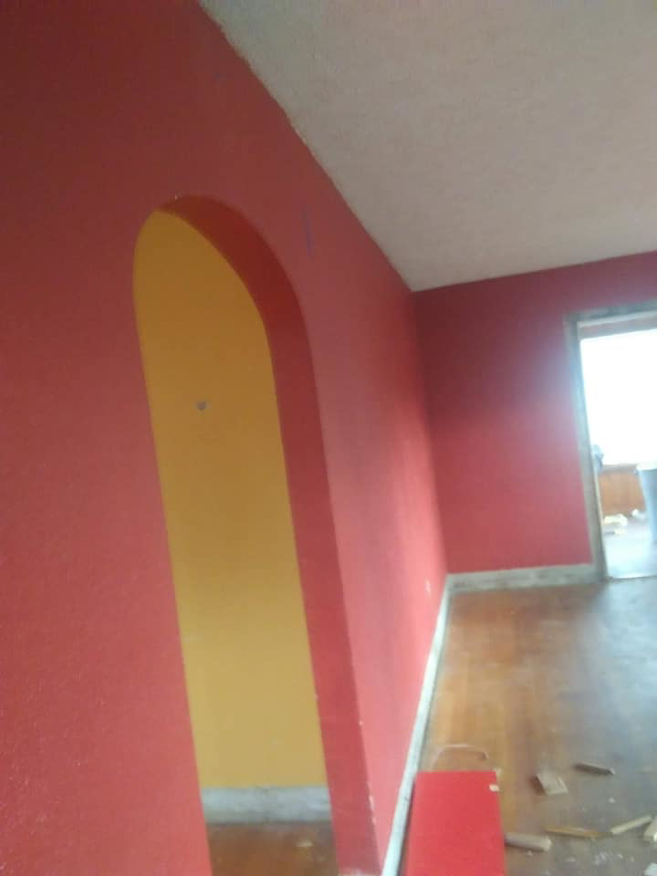 An interior room featuring red painted walls and an arched doorway with a yellow interior, showcasing renovation work by Any Length Improvements in Bowling Green, KY.
