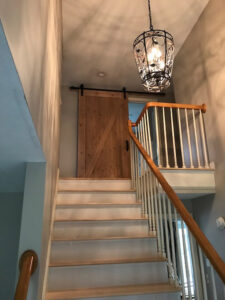 An interior staircase with a newly installed barn door at the top landing, completed by Sini's Handyman Services in Falmouth, ME.