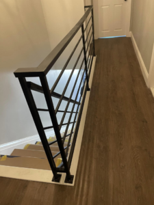 An interior staircase featuring modern black iron railings and wood flooring by AC Fence and Ironworks in Philadelphia, PA.