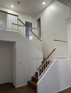 A newly remodeled interior staircase with white railings and wooden handrails by Arizona Contracting And Remodeling LLC in Tucson, AZ