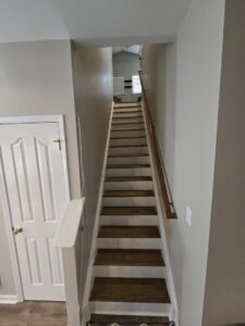 A renovated interior staircase with new wooden treads and white risers by Home FREA in Raleigh, NC.