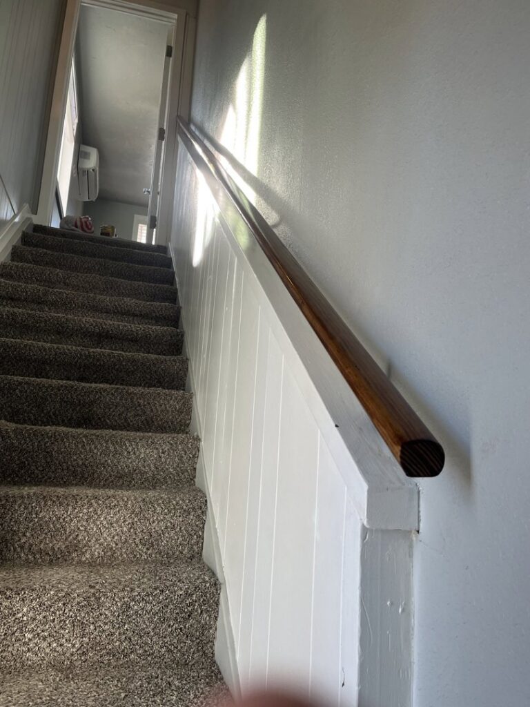 An interior staircase with carpet and a newly installed wooden handrail, a renovation by Forever Young Handyman Services in Boise, ID.