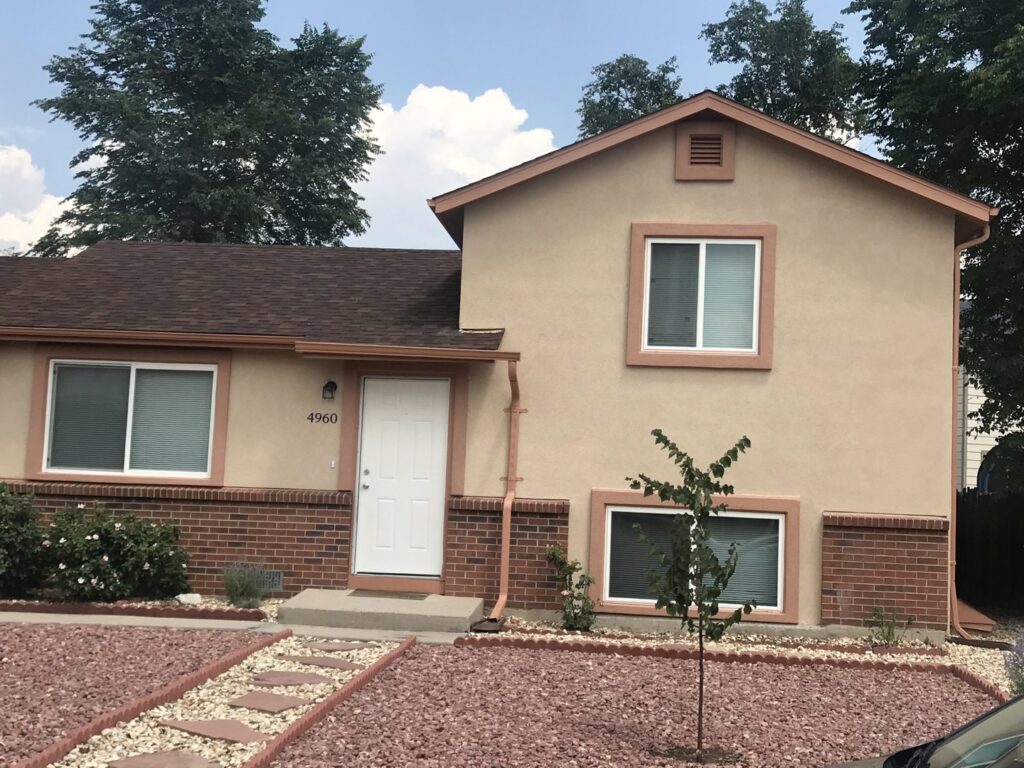 An interior stone fireplace with a wooden mantel and artwork, a renovation by Greg Unseth Painting & Exteriors in Colorado Springs, CO