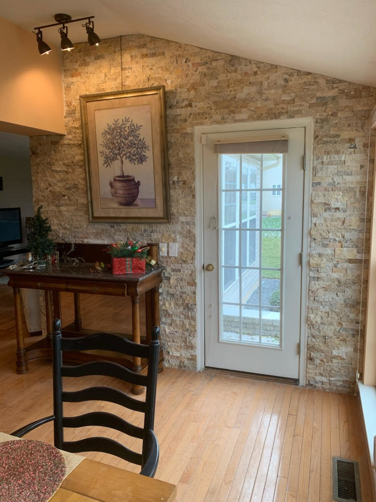 An interior wall featuring decorative stone veneer installation and a glass door, completed by Pink Rose Home Service in Rochester, NY.