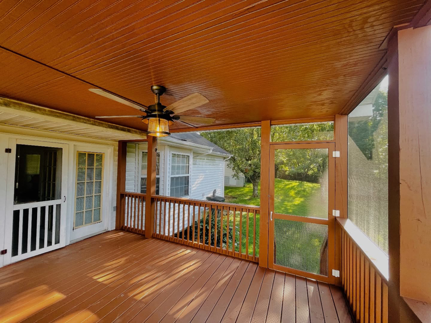 An interior view of a finished screened-in porch with a ceiling fan and wooden floor by Music City Home Experience in Nashville, TN.