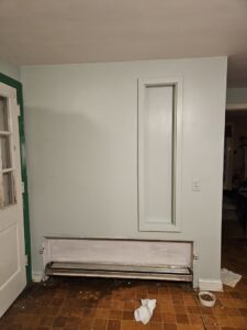 An interior wall with a baseboard heater and recessed panel, showing general handyman repair work by AA Asbestos Abatement, LLC in Portland, CT.