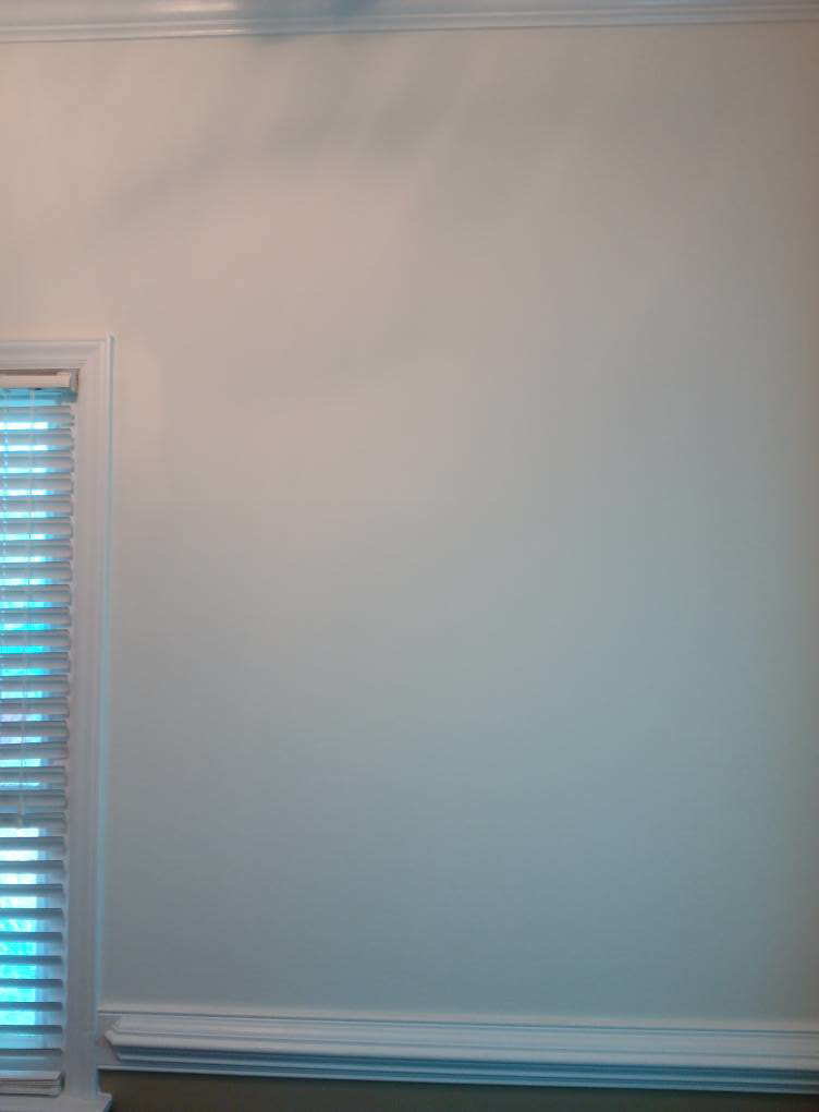 An interior wall showcasing newly installed crown molding and baseboards by Quiros Remodeling in Greenville, SC.