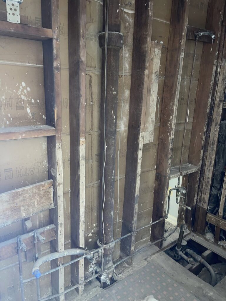 An interior wall stripped down to studs and exposed plumbing, showing demolition work by JPC Junk Removal & Demolition in Philadelphia, PA.