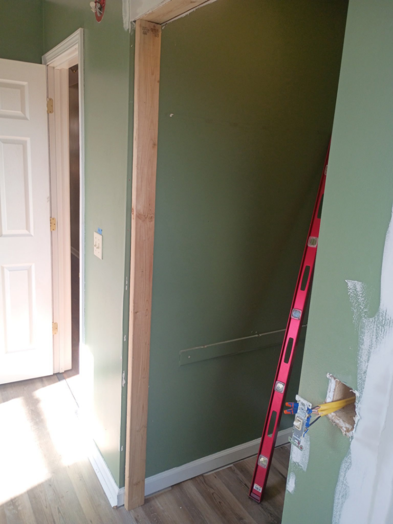 Interior wall framing with electrical rough-in and a level, indicating renovation work by NewEra Construction & Solutions in Lexington, KY