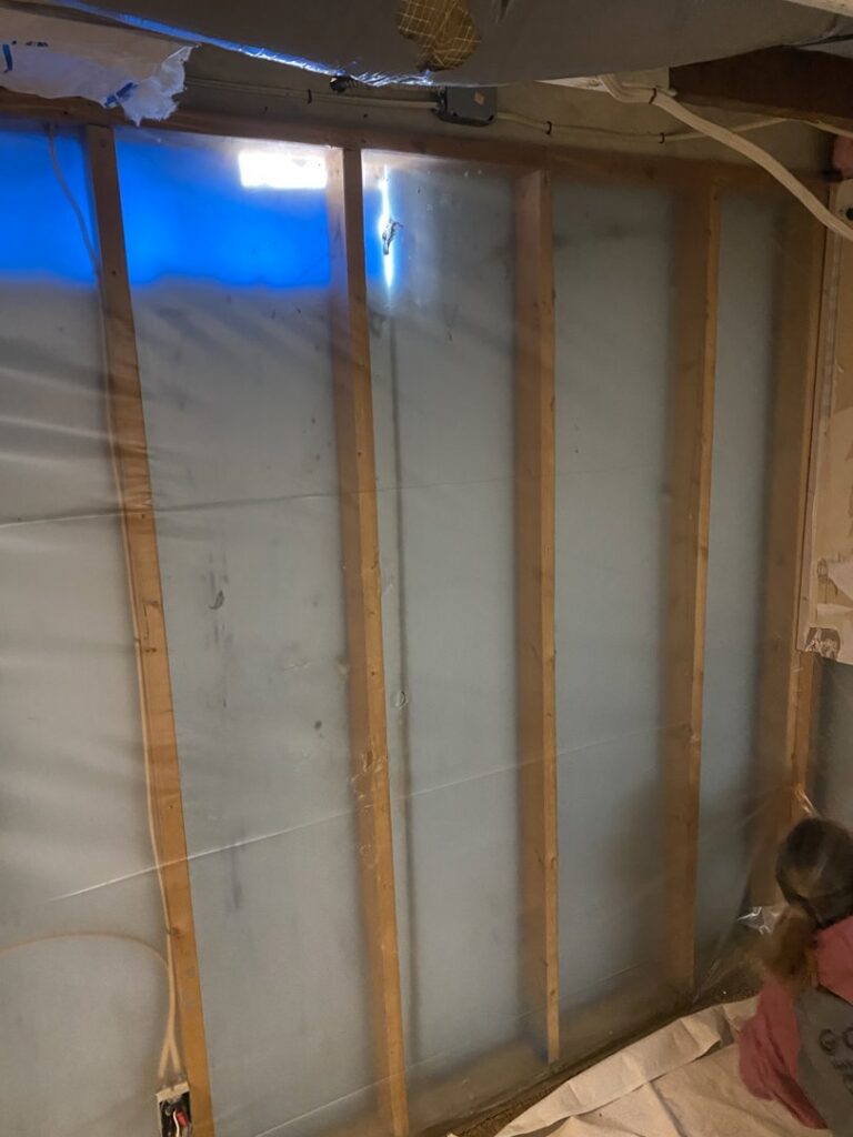 Interior wall framing with a vapor barrier being installed, a service provided by Aaron's Handyman Service in Tucson, AZ.