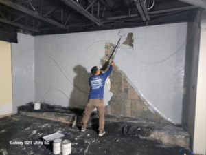 A worker painting an interior wall with a roller for Juan M Construction LLC in Waterbury, CT.