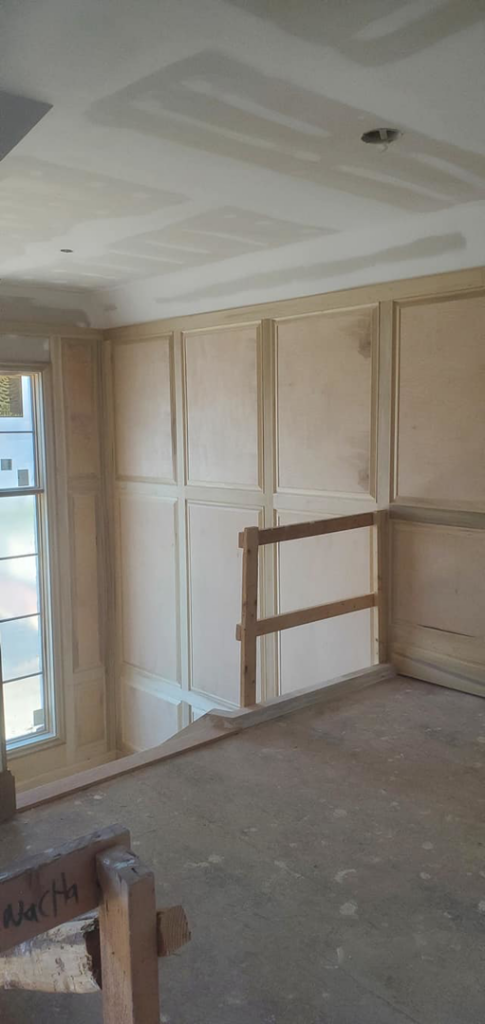Handyman installing decorative interior wall paneling and trim work by Sanchez Construction Services in Laredo, TX.