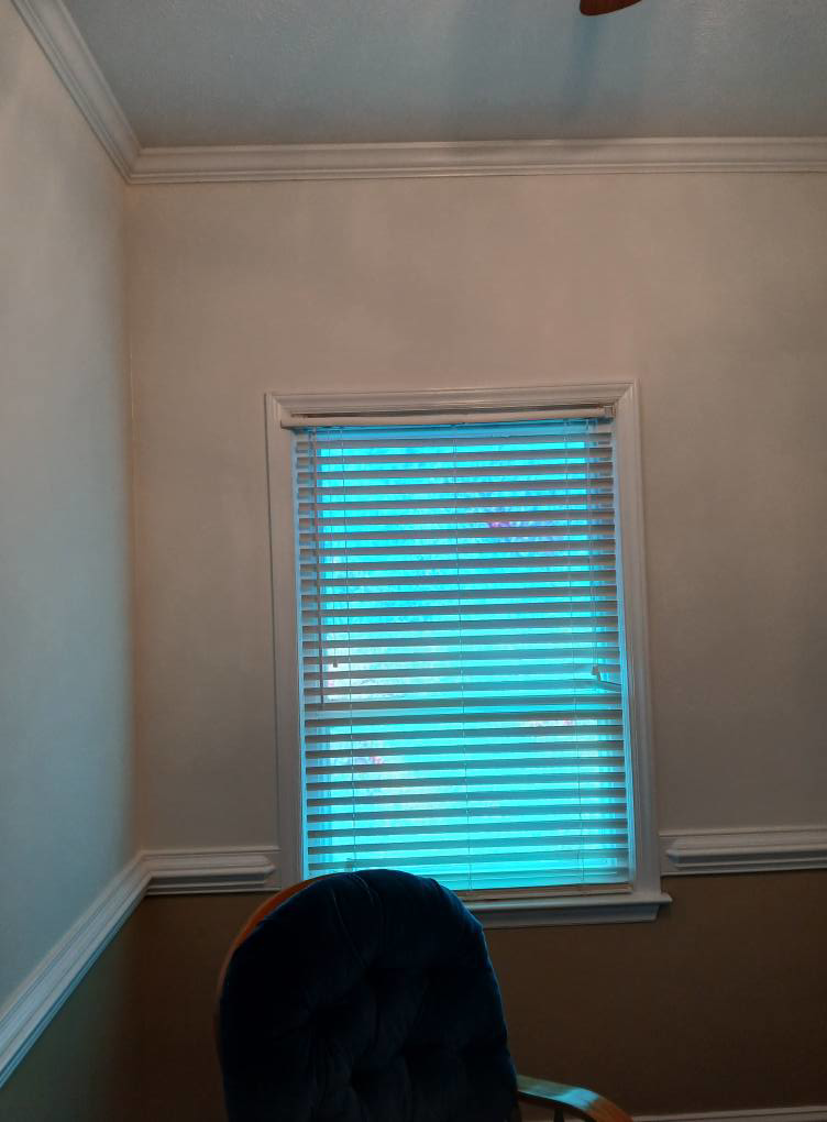 An interior window with blinds, featuring new crown molding and baseboards installed by Quiros Remodeling in Greenville, SC.