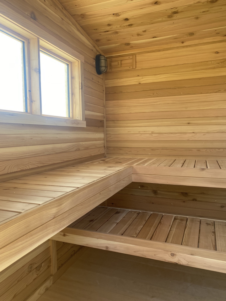 Interior view of a custom wooden sauna with benches and a window by No Boundaries Tiny Homes in Eau Claire, WI