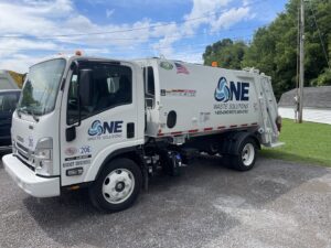 A white Isuzu garbage truck with the One Waste Solutions logo parked in Murfreesboro, TN, used for efficient junk removal.