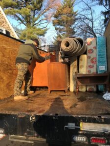 A JDog Junk Removal & Hauling Capital Region NY employee loading mattresses and furniture into a truck in Schenectady, NY.